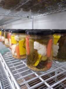 Pickle Cottage jars without labels on shelves during the canning process.
