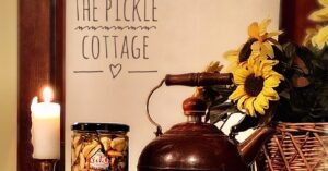 Pickle Cottage tea kettle, sunflowers, and jar of product.